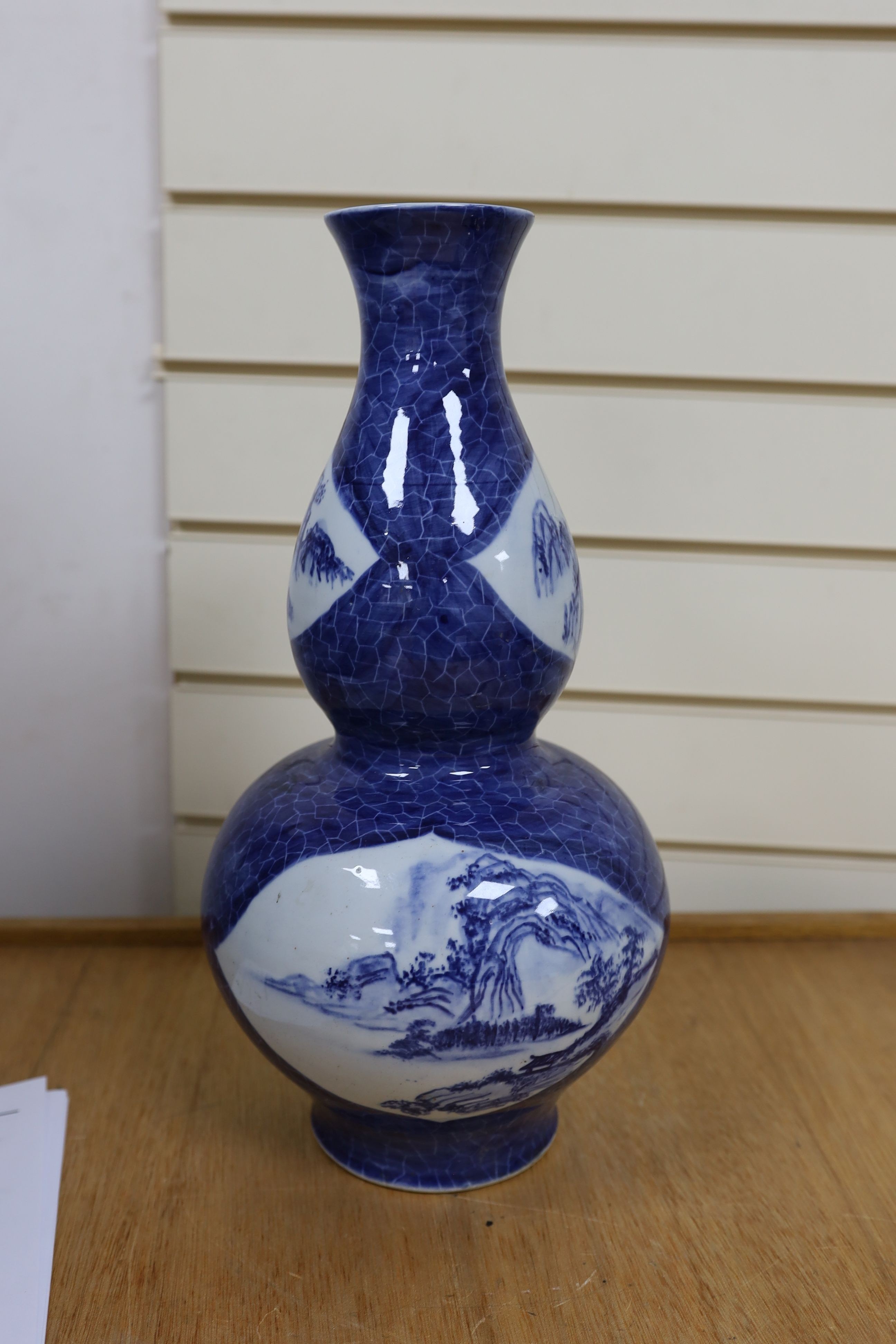 A Chinese blue and white gourd vase with landscape decoration, a similar blue and white sleeve vase and a Japanese Kutani vase